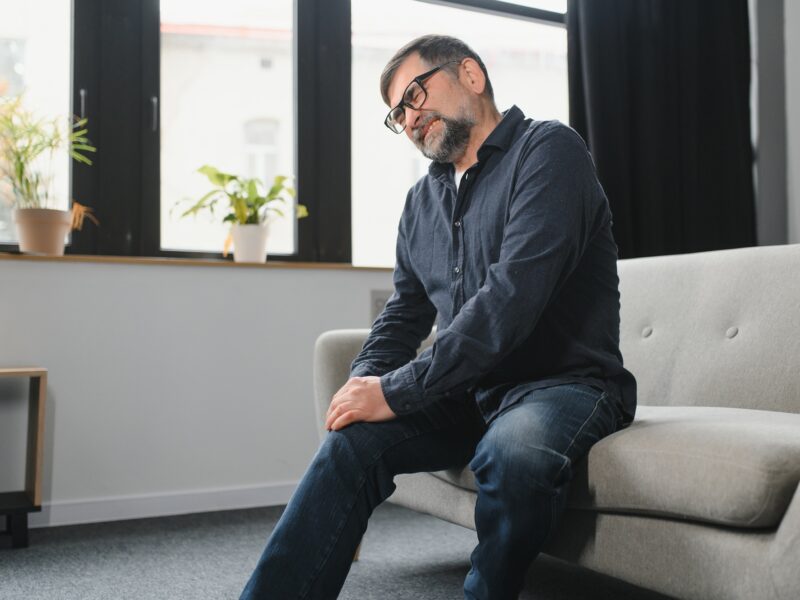 Senior man suffering from pain in knee at home