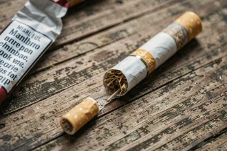 Gros plan macro d'une cigarette Marlboro Light posée sur une surface en bois usé, révélant le filtre et le tabac intérieur, avec un paquet froissé montrant l'avertissement sanitaire